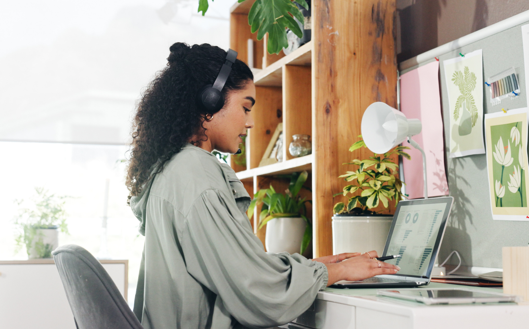 Woman working on a laptop at a home office desk with headphones