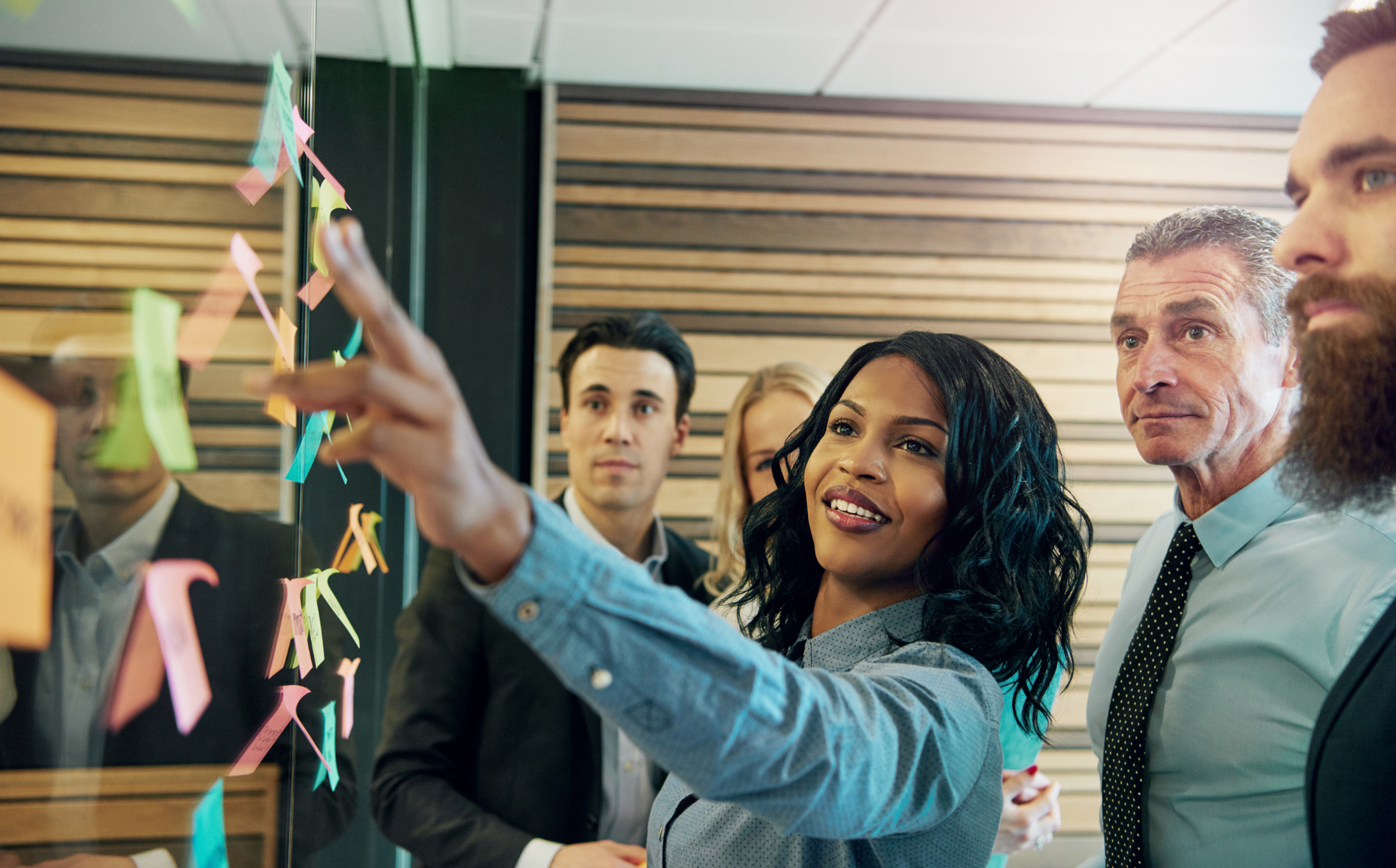 Team collaborating around a glass wall with colorful sticky notes