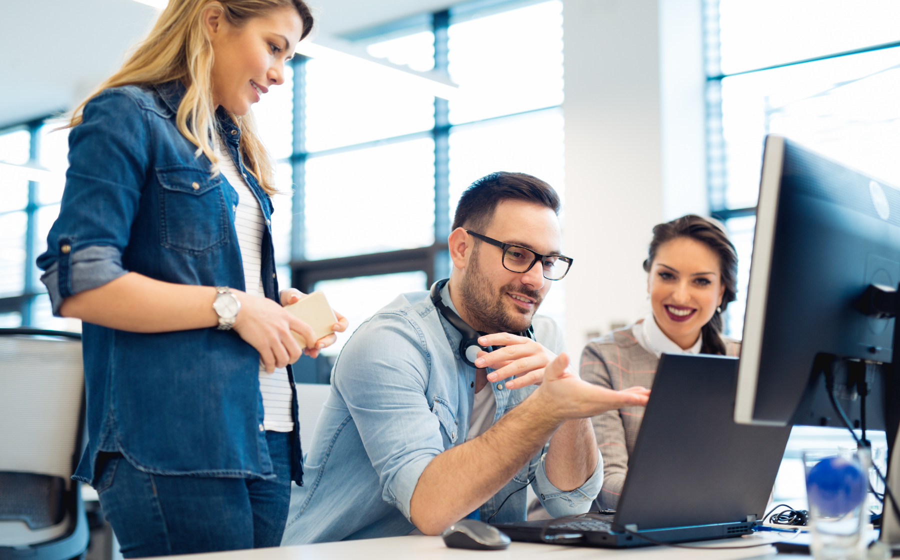Team members collaborating around a laptop at a desk