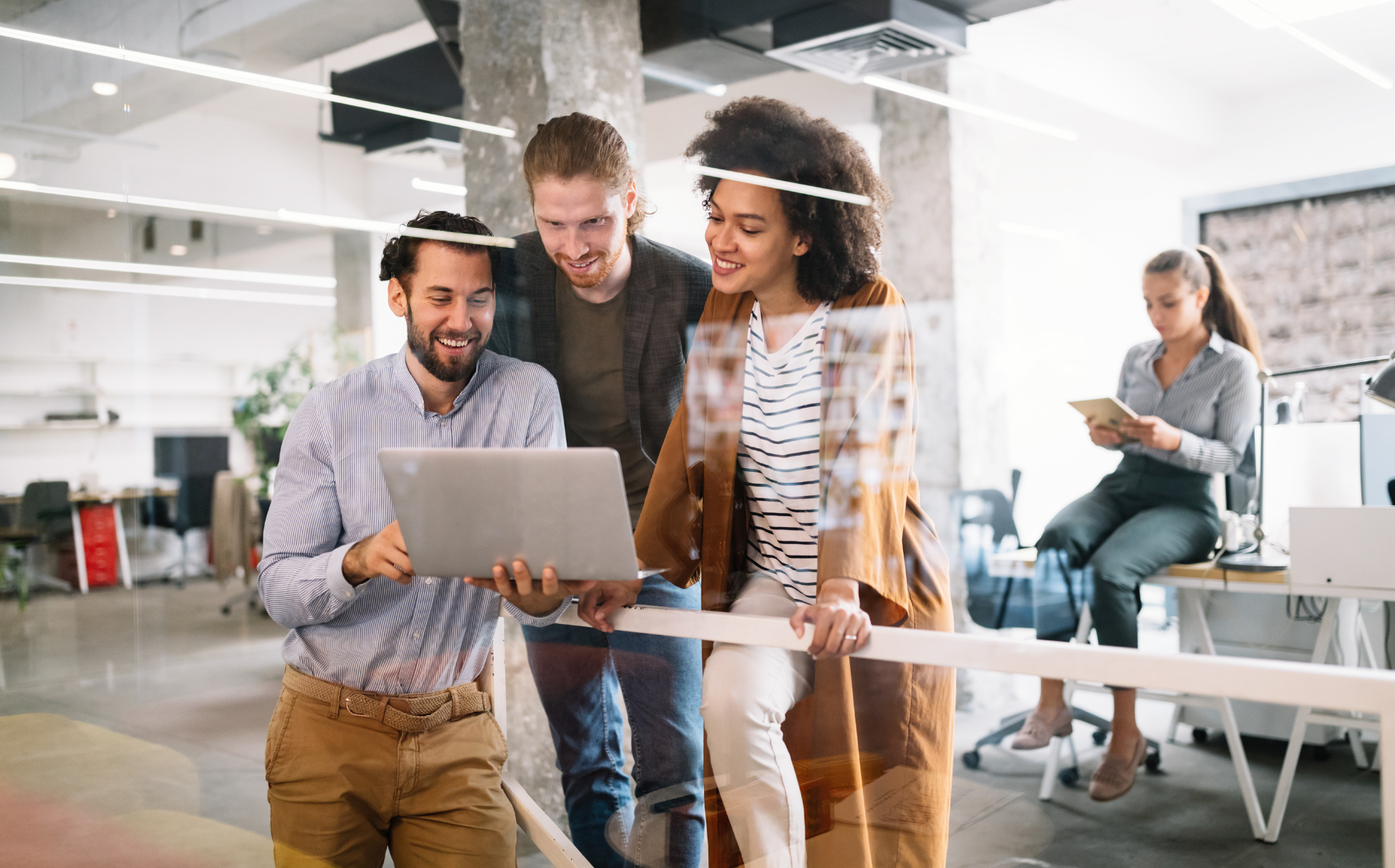 Colleagues reviewing a laptop together in an open office