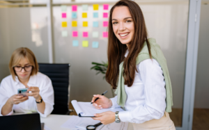Woman smiling while holding a notebook in an office
