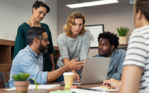Team collaborating around a laptop in a modern office