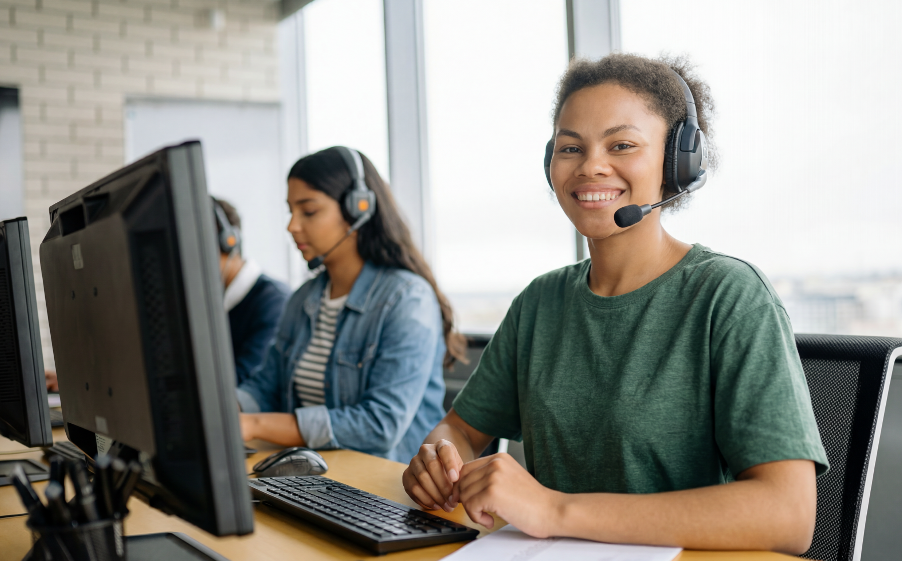 Customer support representative wearing a headset at a computer.