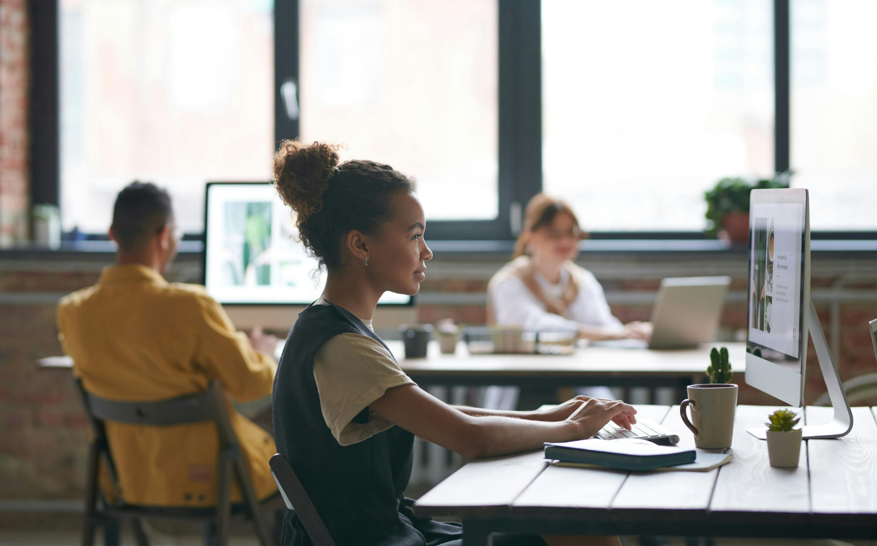 Woman working on a desktop computer in a shared workspace