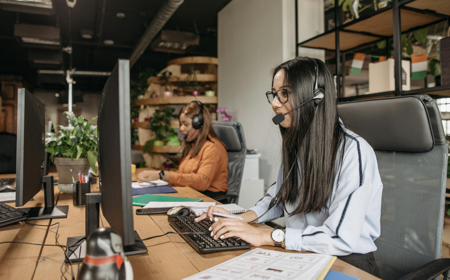 Customer support representatives working at computers with headsets.