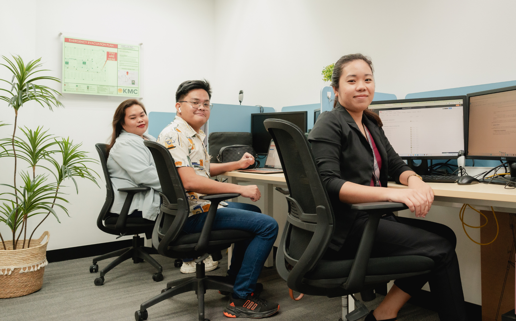 Three team members working at computer stations in a modern office