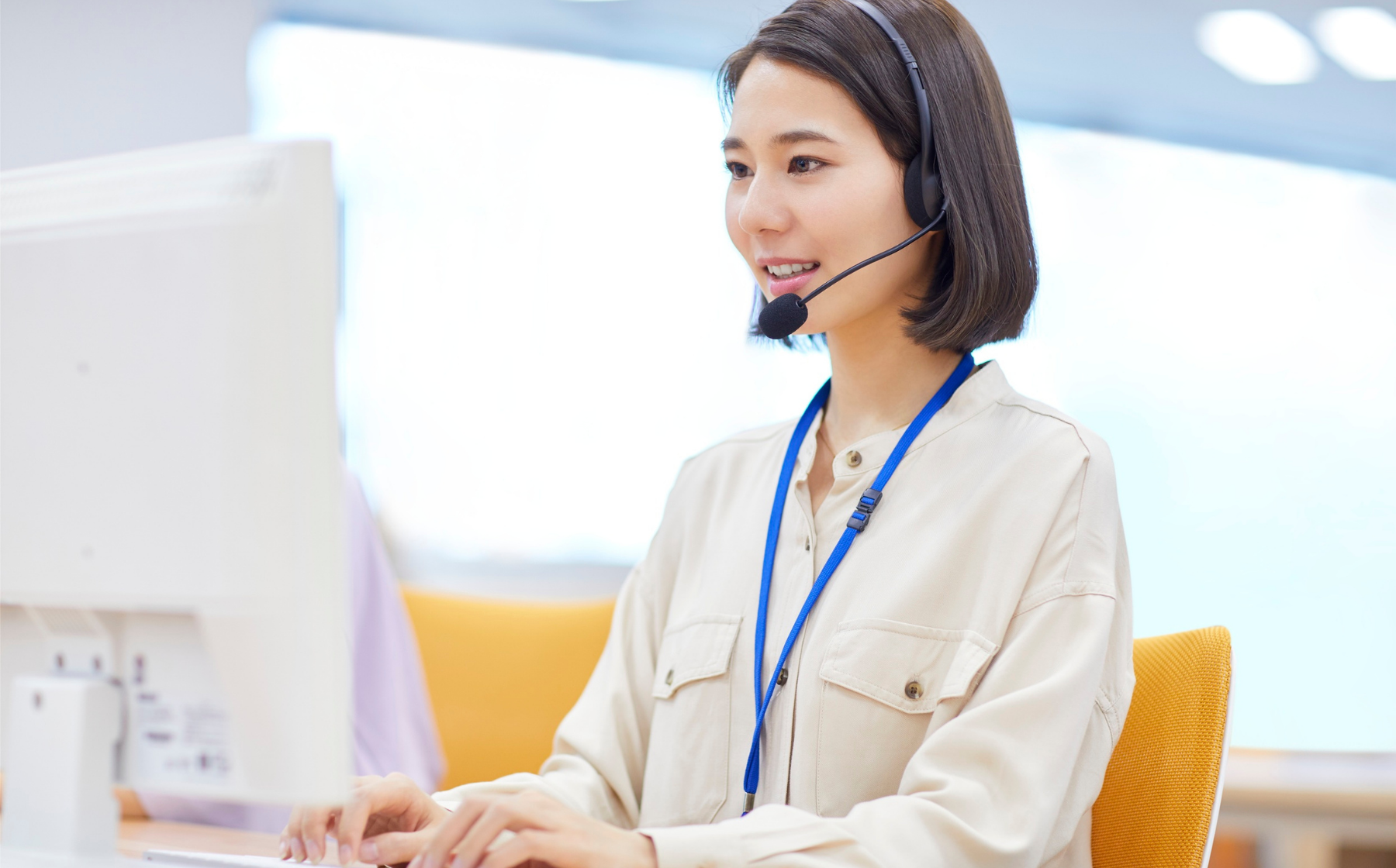 Customer service representative wearing a headset works at a computer