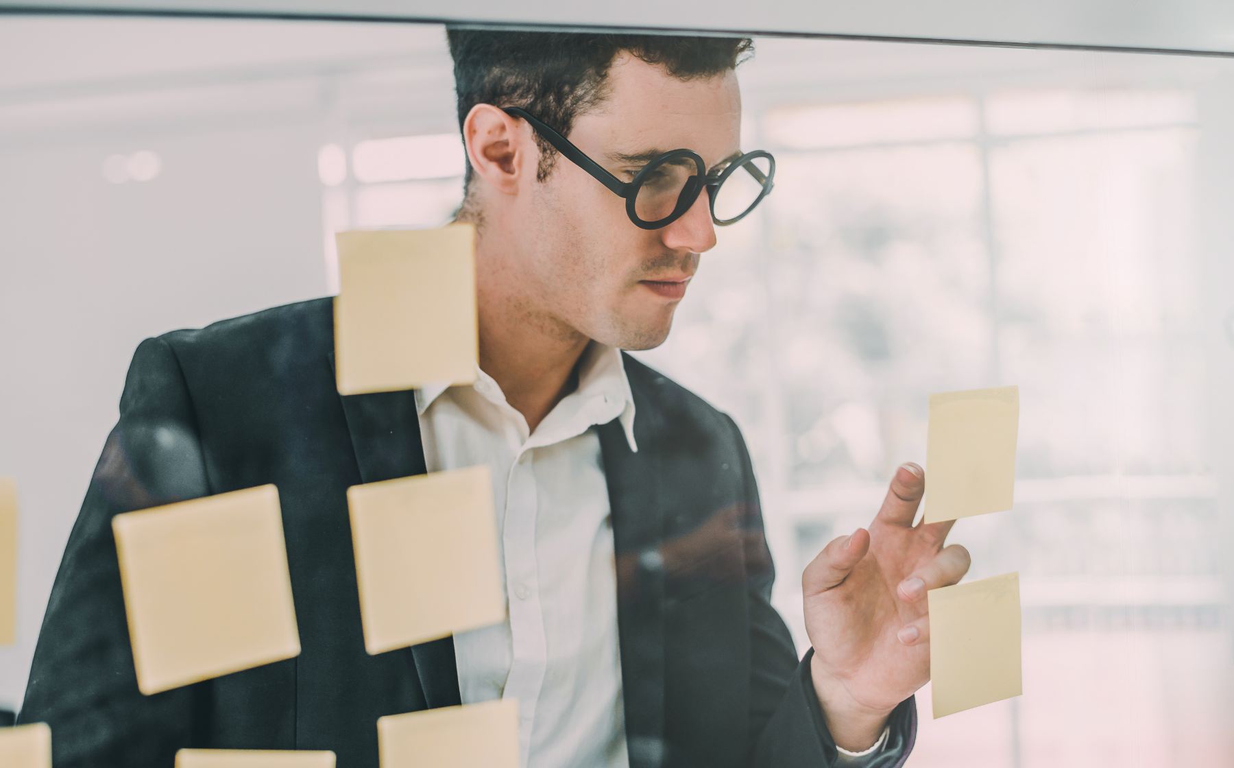 Leader organizing ideas with sticky notes on a glass wall